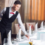 Waiter Serving Table In The Restaurant Preparing To Receive Gues