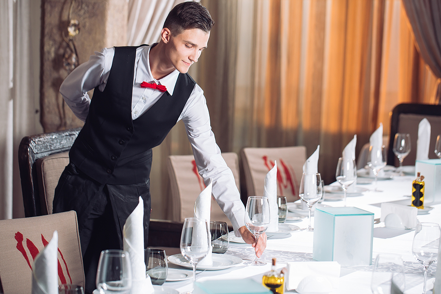 Waiter Serving Table In The Restaurant Preparing To Receive Gues